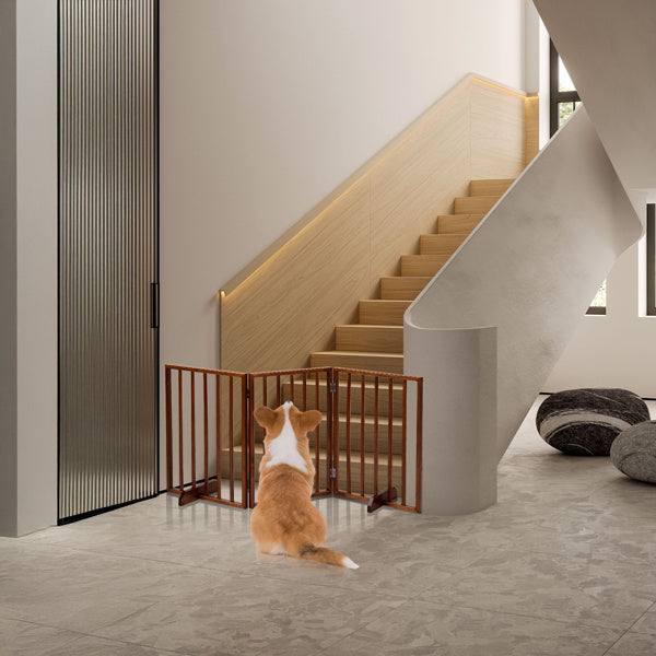 Brown wooden dog gate installed at the bottom of stairs with a small dog sitting nearby