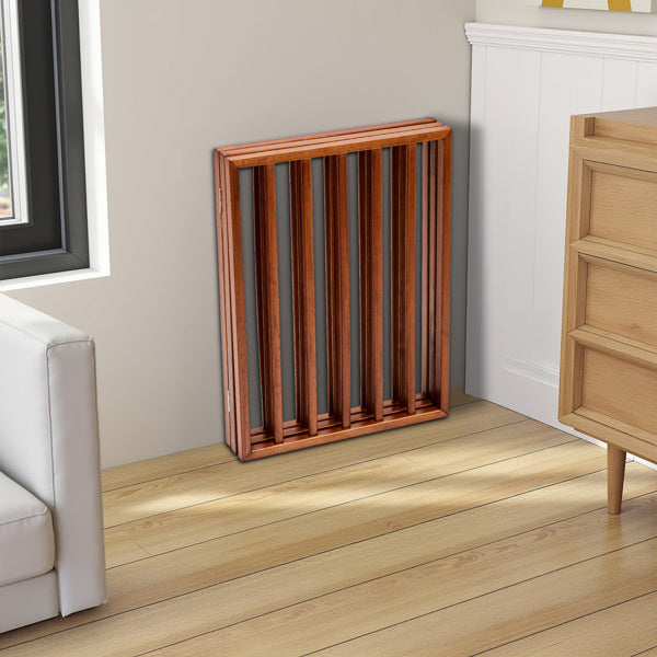 Brown wooden dog gate with vertical slats leaning against a wall in a bright living room corner