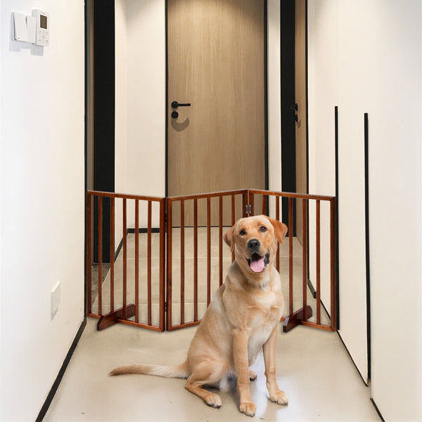 Brown wooden dog gate placed in a hallway with a sitting golden retriever in front