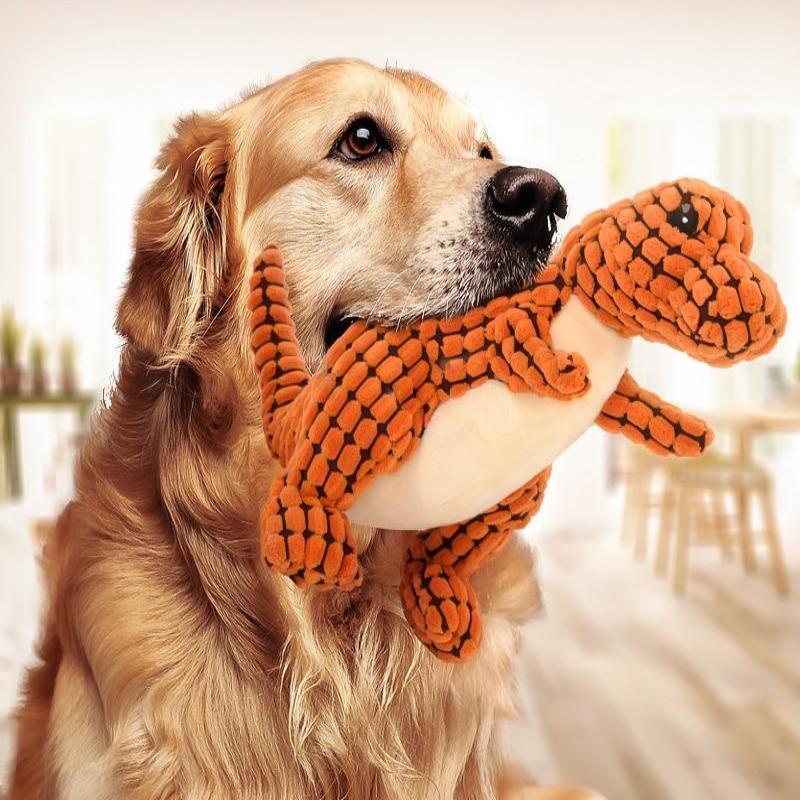 Golden retriever holding a plush orange dinosaur dog toy for large dogs from Pet Pleasers Shop
