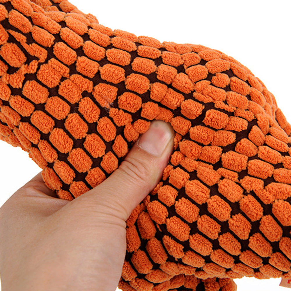 Pet Pleasers Shop dinosaur dog toy for large dogs in textured orange plush material held by hand